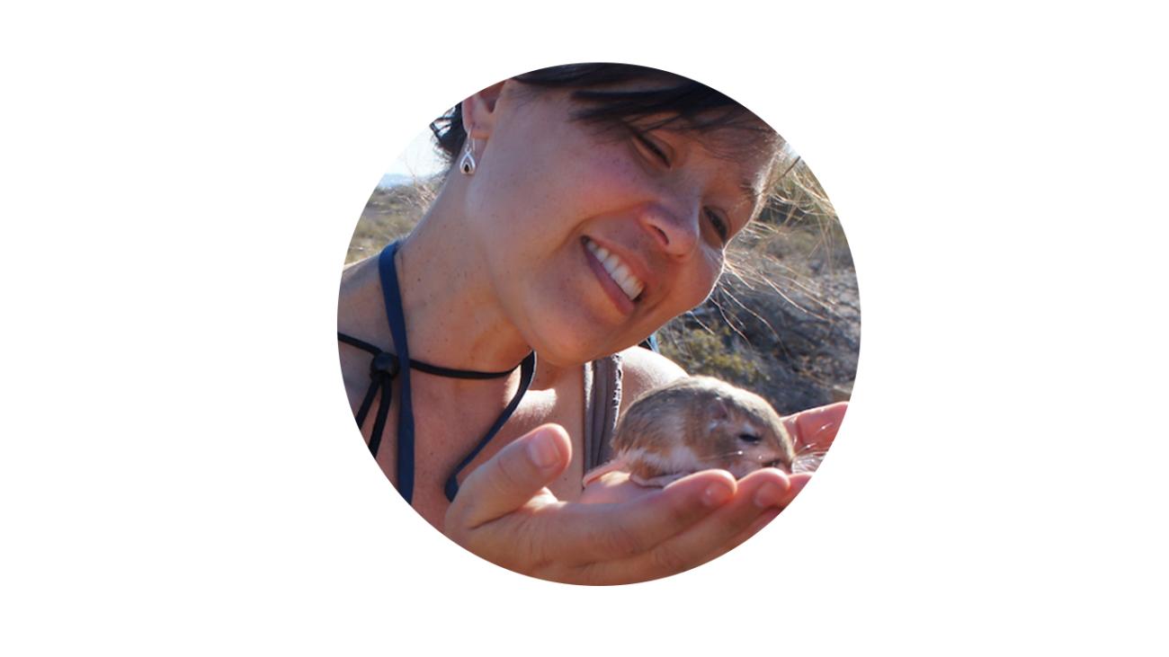 A girl cradles a kangaroo rat in the palm of her hands.